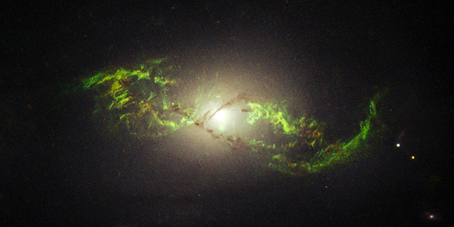 NGC 5972 – Hubble-Aufnahme einer Galaxie mit grün leuchtenden Gasstrukturen um einen Quasar